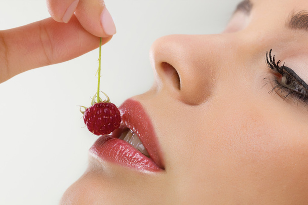 mooie vrouw eten zoete frambozen, close-up - Foto, afbeelding