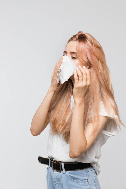 Portret młodej pięknej kobiety dmuchającej nos w papierową serwetkę, patrząc na lewą / zimną, kichanie, objawy alergii, grypa, nieżyt nosa, choroby, rozpaczliwie chore, koncepcja opieki zdrowotnej i medycyny - Zdjęcie, obraz