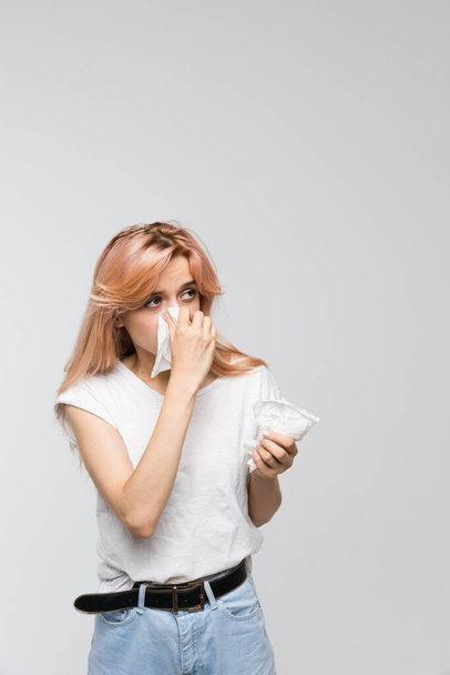 Portrét roztomilé ženy fouká nos do papírového ubrousku, vypadá na zdroj alergie / nachlazení, kýchání, příznaky alergie, chřipka, rinitida, nevolnost, zoufale nemocný, zdravotní a lékařské pojetí - Fotografie, Obrázek
