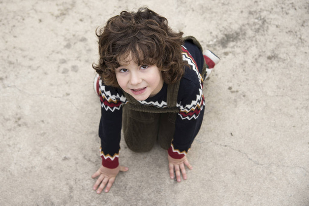 little boy with curly hair and without a tooth posing with a green bib - Foto, Bild