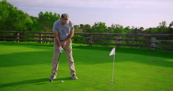 Mooie oudere golfer swingende golfclub, golfen in het paradijs. - Video