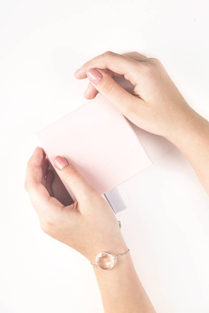 Las manos femeninas sostienen una caja con un regalo en colores pastel
 - Foto, Imagen