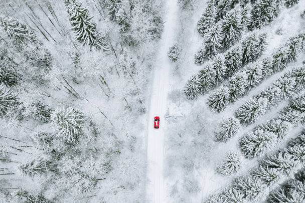 Antenni ylhäältä näkymä lumen peittämä metsä talvella tie ja punainen auto
.  - Valokuva, kuva
