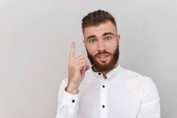 Image of bearded surprised man pointing finger upward - Photo, image