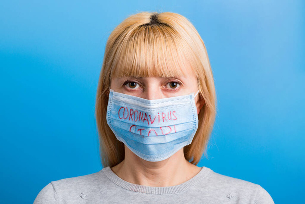 Ritratto di donna in maschera medica con testo di arresto coronavirus su sfondo blu. Concetto di Coronavirus. Protezione delle vie respiratorie
 - Foto, immagini