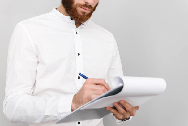 Cropped image of focused handsome man writing and holding clipboard - Foto, immagini