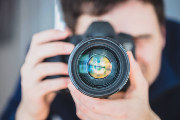 Fotograaf staat achter een professionele camera met telelens op een statief - Foto, afbeelding