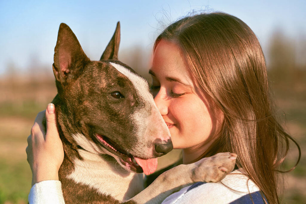 Young girl walks with bull Terrier in fresh air - Foto, Bild