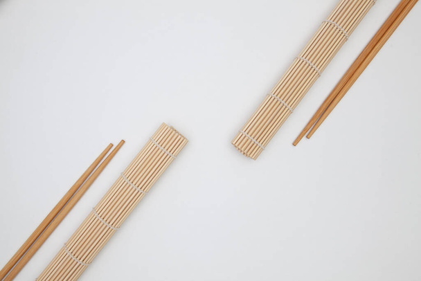 Bamboo mat with chopsticks for sushi on the white table.  - Photo, image