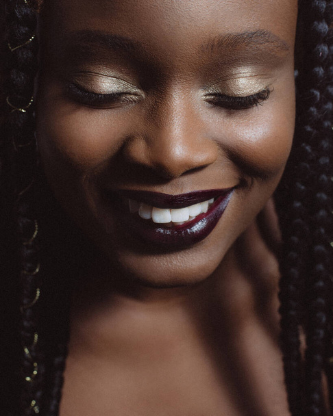 Belo retrato de uma mulher afro-americana com maquiagem elegante com os olhos fechados e sorriso
 - Foto, Imagem