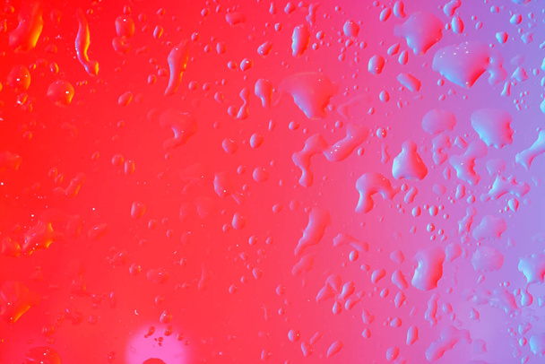 Drops of water on a glass sheet with flashes and color film Photographed in the studio - Photo, Image