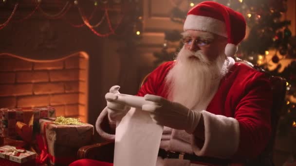 Santa Claus rolls up a scroll on Christmas eve and checks the list of children to whom gifts are prepared. Fantastic atmosphere - Video, Çekim