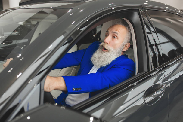 車の中の老人。車の中でひげを生やした成熟した男性。車を購入するビジネスマンを自信を持って. - 写真・画像