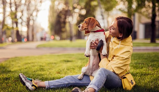 Cheerful woman with dog sitting in park - Photo, image