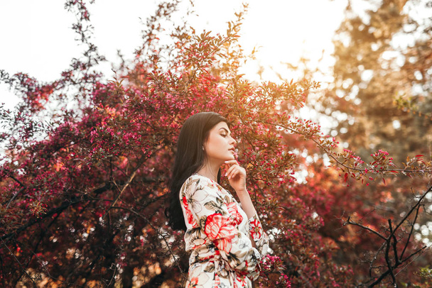 Elegant woman near blooming bush in garden - Photo, Image