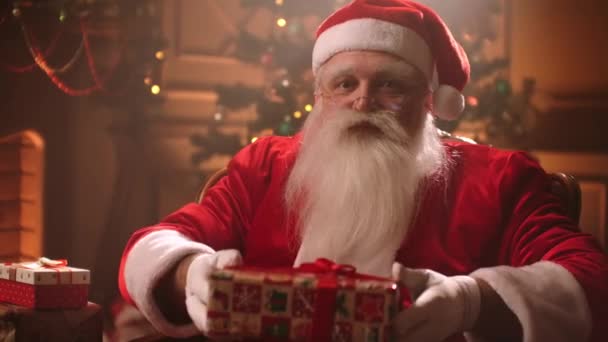 Санта Клаус дарит подарки и улыбается
 - Кадры, видео