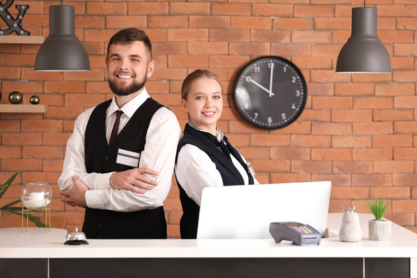 Mannelijke en vrouwelijke receptionisten bij Bureau in hotel - Foto, afbeelding