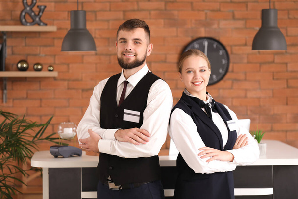 Mannelijke en vrouwelijke receptionisten in de buurt van de receptie in het hotel - Foto, afbeelding
