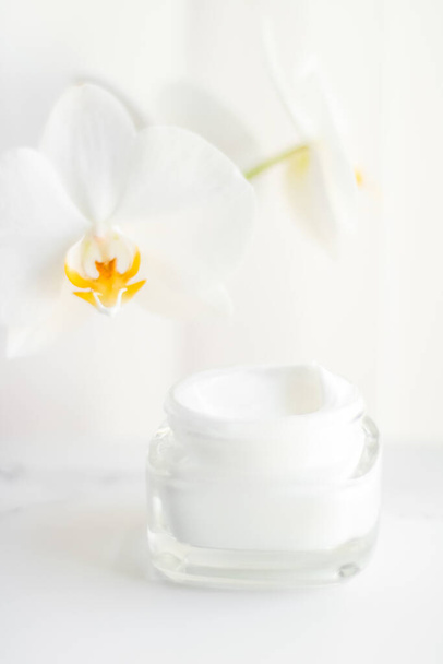 Face cream moisturizer jar and orchid flower, moisturizing skin  - Fotó, kép