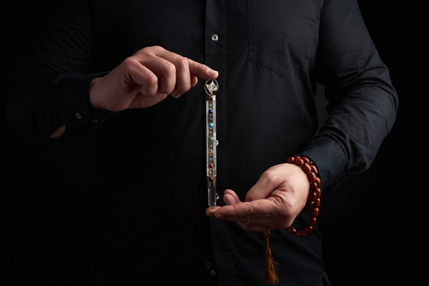 adult man in a black shirt holds a crystal chakra rod inlaid wit - Fotoğraf, Görsel