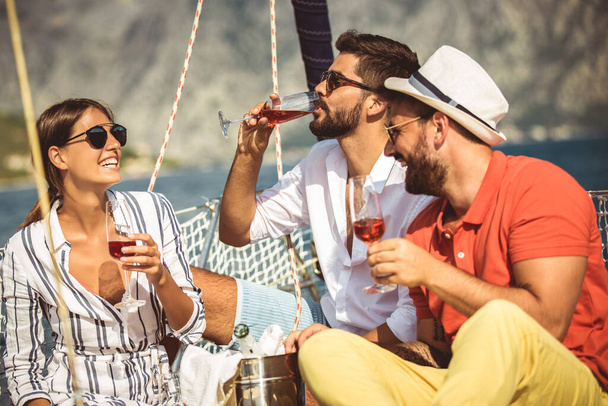 Улыбающиеся друзья с бокалами шампанского на яхте. Отпуск, тр
 - Фото, изображение