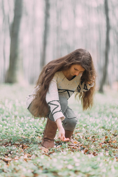 pretty young girl with long hair walking through the green forest in the spring - Photo, Image