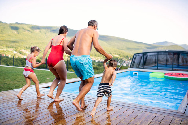Rear view of family with two small children by swimming pool outdoors. - Fotoğraf, Görsel