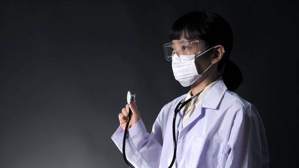 Asia giovane donna medico con virus protettore maschera e occhiali in studio colore nero sfondo che rappresentano circa coronavirus focolaio che pandemia nel distretto di Wuhan in Cina e molte persone infette
. - Foto, immagini