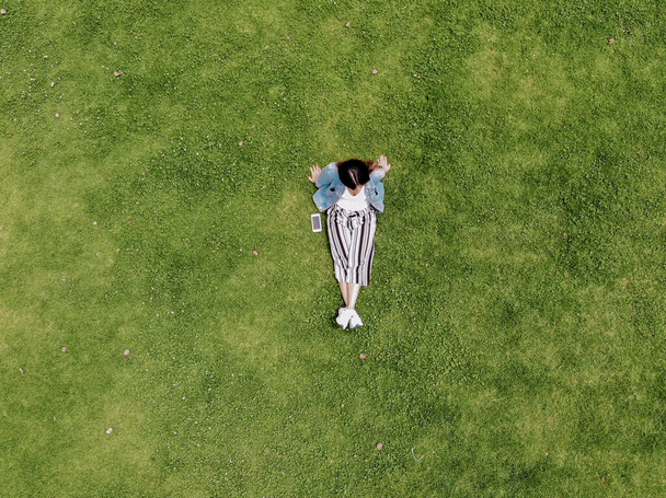 Femme assise sur l'herbe d'en haut avec jean et pantalon de lignes
 - Photo, image