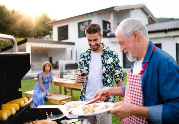 Portrait of multigeneration family outdoors on garden barbecue, grilling. - Foto, Imagen