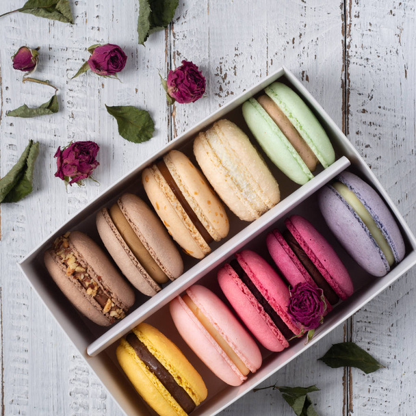 Colorful macarons into a box on the white wooden table background. Macaroons close up. Flat lay top view.  - Φωτογραφία, εικόνα