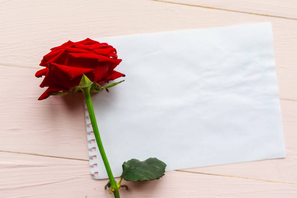 Красная роза и белый макет бумаги пустой на деревянном фоне. Плоская лежала, вид сверху, копировальное пространство. Открытки на день святого Валентина или на день матери
 - Фото, изображение