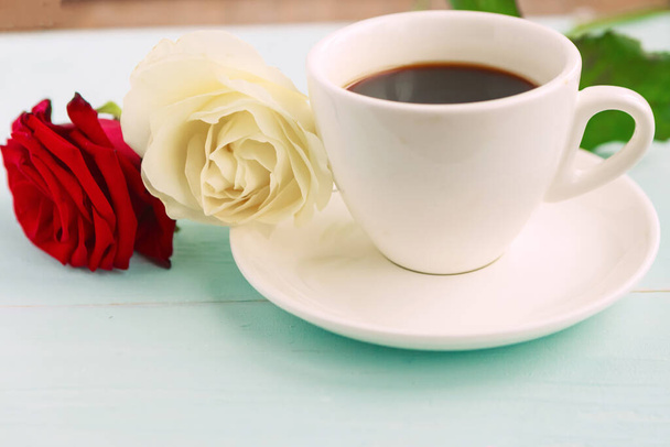 Кофейная чашка и белые и красные розы на деревянном столе
 - Фото, изображение