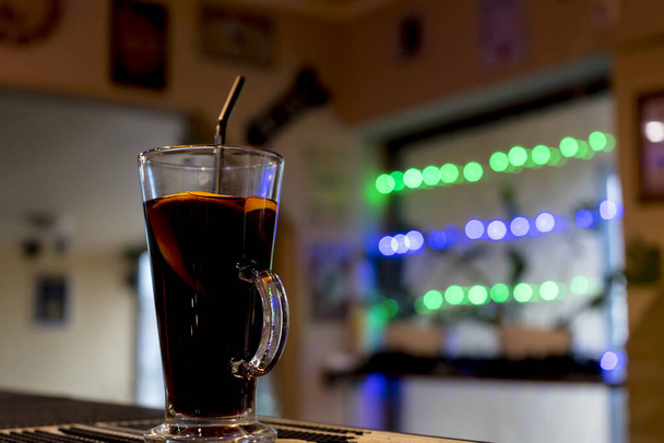 Un verre de vin chaud et une tranche d'orange est sur le bar, l'éblouissement du soleil et l'éclairage
 - Photo, image