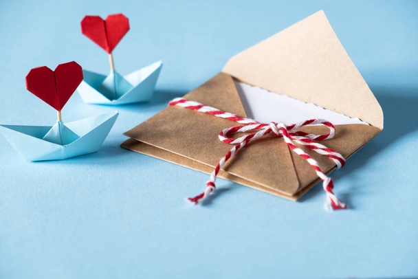 Valentin-napi szerelmes levél mockup. Kézműves boríték fehér üres kártyával és kék hátterű szívekkel. Valentin-nap, Anyák napja, Nőnapi üdvözlőlap. - Fotó, kép