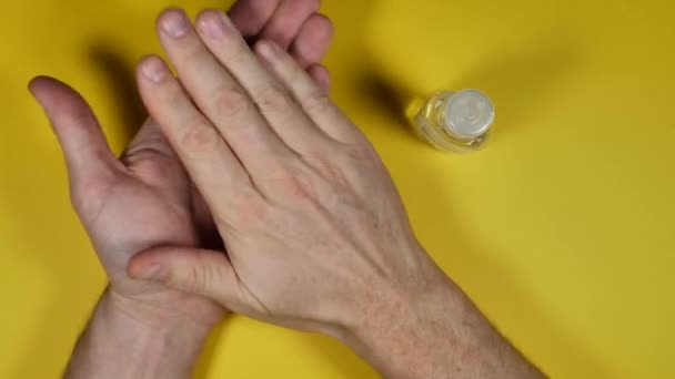 partial top view of person cleaning hands with sanitizer on yellow background - Séquence, vidéo