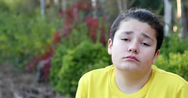 Portrait of a young handsome teenager sitting on park bench alone - Felvétel, videó