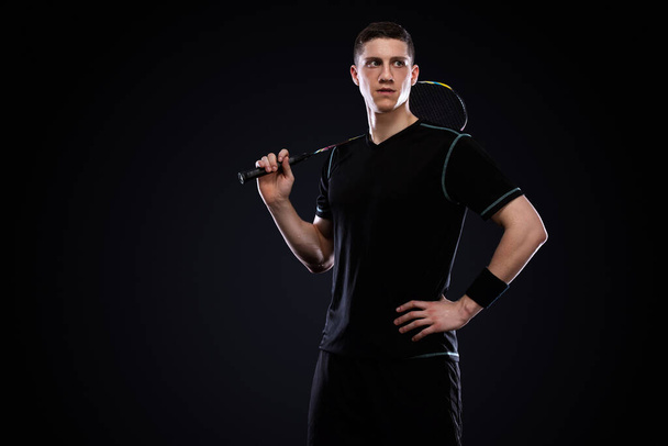 Badminton player in sportswear with racket and shuttlecock on black background. Olympic game. - 写真・画像