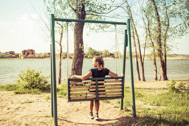 Young woman swinging on a swing. Girl sitting on a swing - Fotó, kép