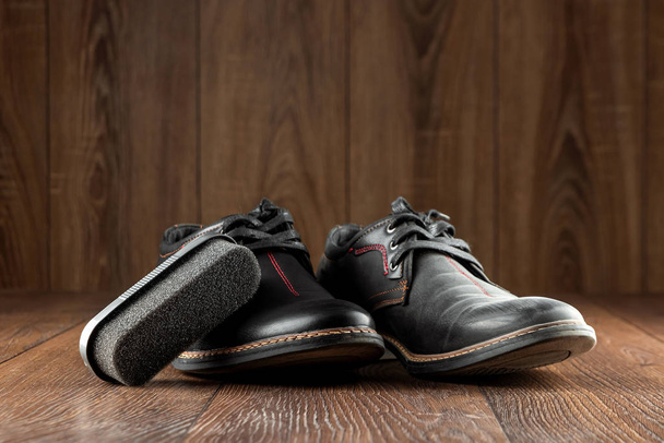 Black shoes one clean second dirty on a wooden background. The concept of shoe shine, clothing care, services. - Photo, Image