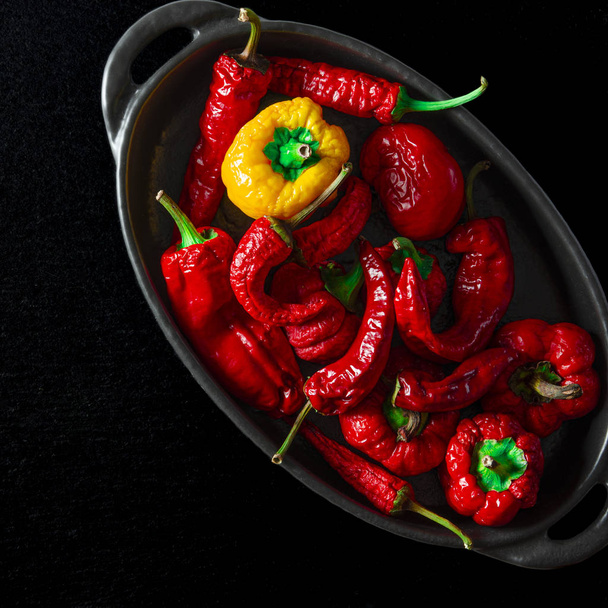 Värikäs kuvioitu chili on mustassa leivinmuodossa
 - Valokuva, kuva