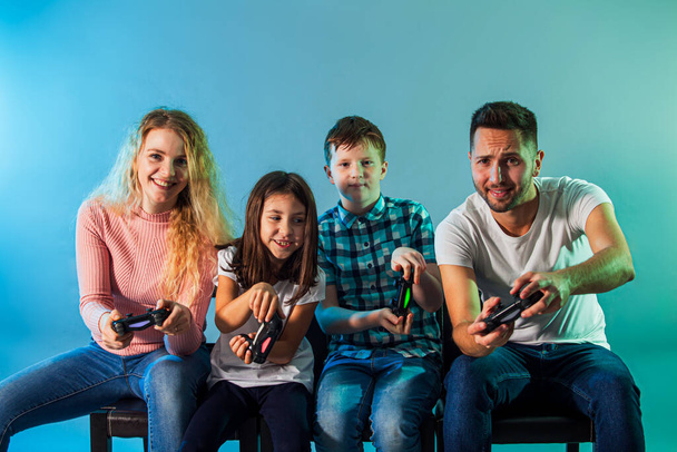 Jonge vrolijke ouders en kinderen spelen videospel samen - Foto, afbeelding