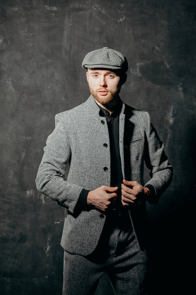 Ready for business. A bearded man in a cap and a gray suit fastens his jacket. - Foto, imagen