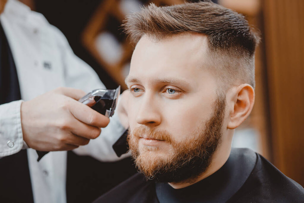 Hairdresser cuts hair men in barbershop. Barber doing correct beard trim electric shaver - Photo, Image