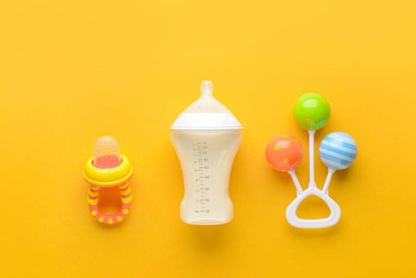 Пляшка молока для дитини та іграшки з соску на кольоровому фоні
 - Фото, зображення
