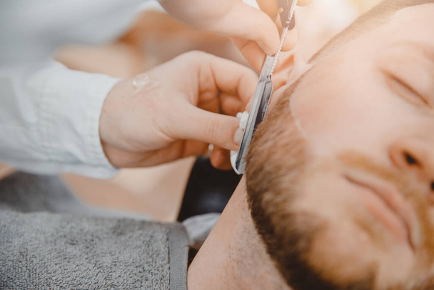 Barber process shaving razor bearded hipster man in barbershop - Photo, Image