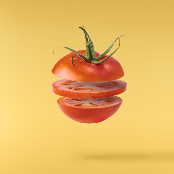 Tomates vermelhos maduros frescos voando no ar isolado no bac amarelo
 - Foto, Imagem