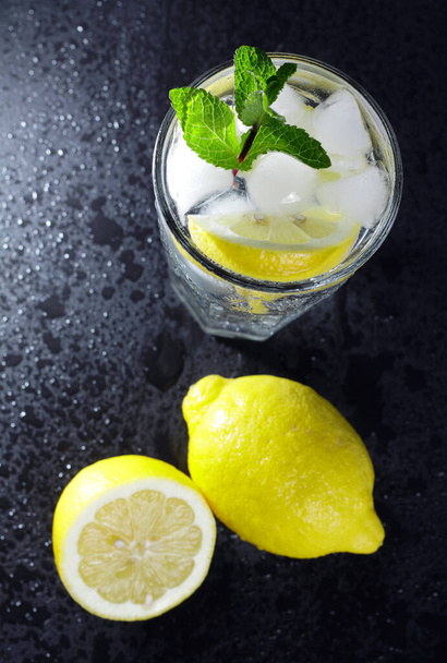glass of lemon and ice on black background - Fotó, kép