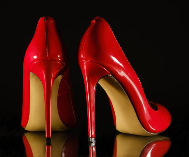 Lackleder glänzende weibliche rote Stilettos auf schwarzem Hintergrund - Foto, Bild