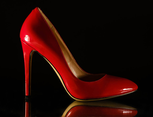patent leather shiny female red stilettos on a black background - Foto, Bild